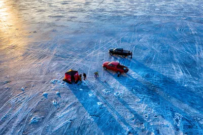 Drone shot of ice fishing scene with tents and trucks on a frozen lake in Minnesota.